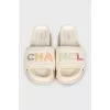 White leather flip-flops with a multi-colored logo