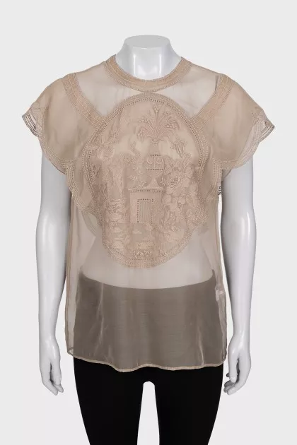 A loose-fitting, transparent blouse decorated with embroidery