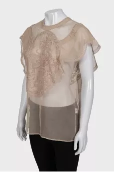 A loose-fitting, transparent blouse decorated with embroidery