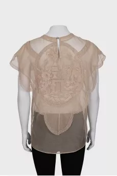 A loose-fitting, transparent blouse decorated with embroidery