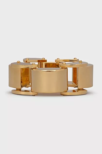 A chunky gold bracelet with a tag