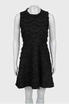 The fitted dress is decorated with tassels