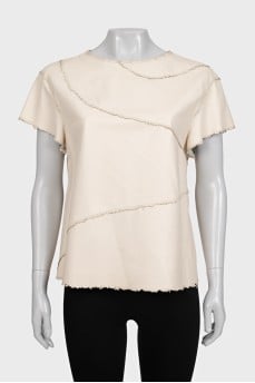 Beige leather top with decorative stitching and tag