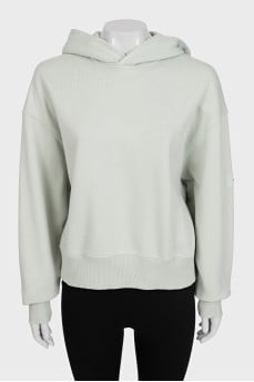 Green hoodie with a logo on the sleeve