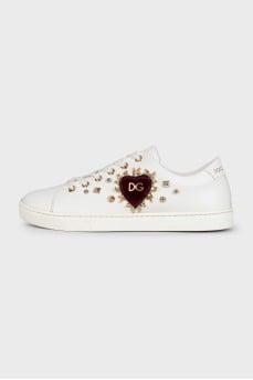 White leather sneakers decorated with studs and a patch