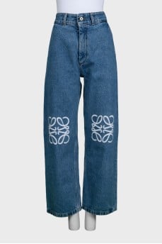 Blue jeans with branded embroidery on the knees