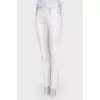 White jeans with a silver coating, with a tag