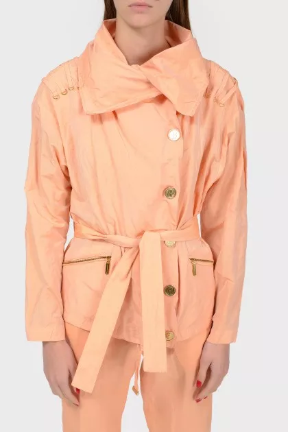 A peach short cloak with an asymmetric fastener on buttons