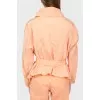 A peach short cloak with an asymmetric fastener on buttons