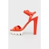 Orange sandals on a white platform