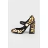 Black and golden shoes with a pearl with a tag