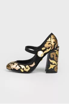 Black and golden shoes with a pearl with a tag