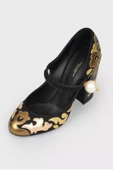 Black and golden shoes with a pearl with a tag