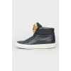 Black leather sneakers with metallic brand logo