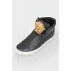 Black leather sneakers with metallic brand logo