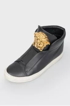 Black leather sneakers with metallic brand logo