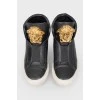 Black leather sneakers with metallic brand logo