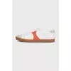 White sneakers with orange inserts and tag