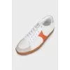 White sneakers with orange inserts and tag