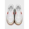White sneakers with orange inserts and tag