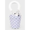 A purple bag with a net and white handles, there is a tag