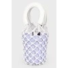 A purple bag with a net and white handles, there is a tag