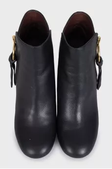 Black leather ankle boots with a gold pendant