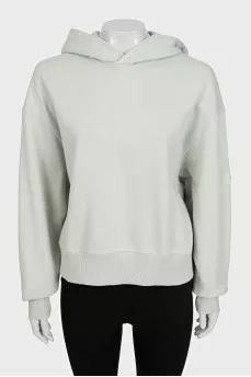 Green hoodie with a logo on the sleeve