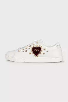 White leather sneakers decorated with studs and a patch