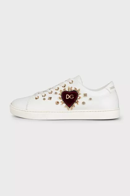 White leather sneakers decorated with studs and a patch