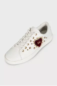 White leather sneakers decorated with studs and a patch