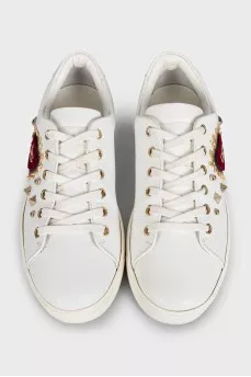 White leather sneakers decorated with studs and a patch
