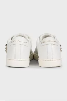 White leather sneakers decorated with studs and a patch