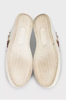 White leather sneakers decorated with studs and a patch